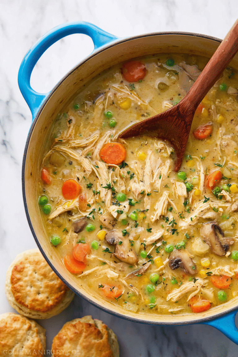 Creamy chicken pot pie soup simmering with peas, carrots, and shredded chicken, served with warm flaky biscuits