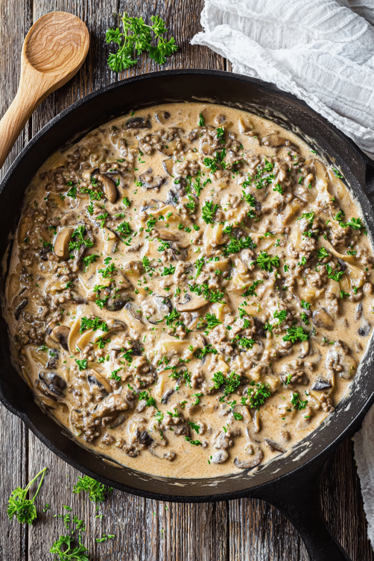 Rich and creamy ground beef stroganoff with mushrooms and onions in a skillet topped with fresh parsley