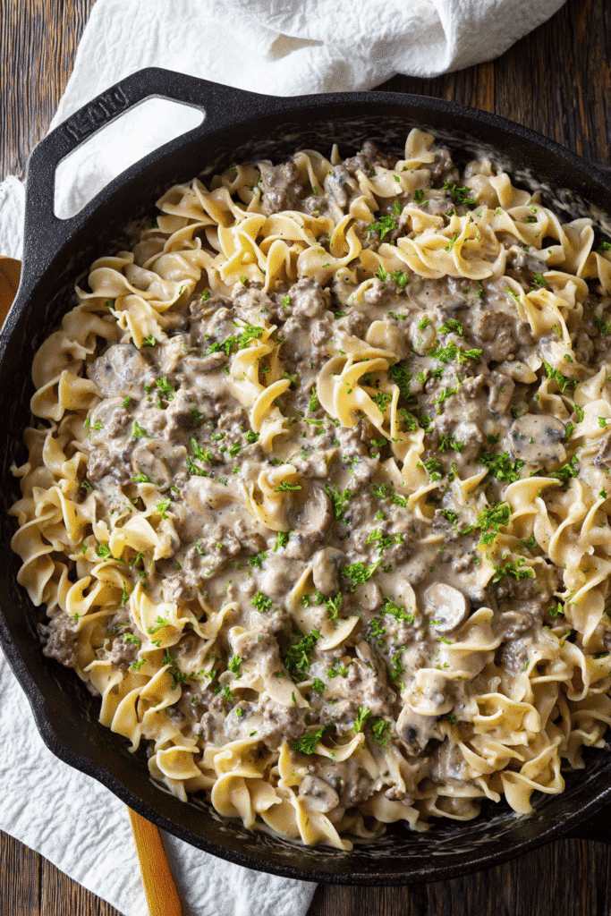 Creamy ground beef stroganoff with egg noodles and mushrooms in a skillet topped with fresh parsley