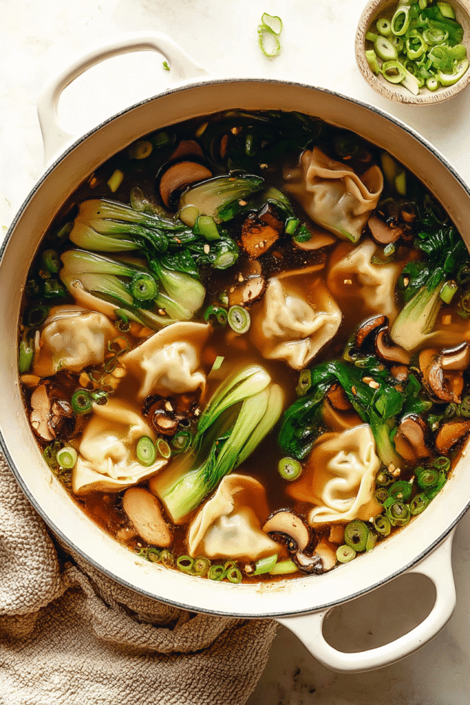 Warm potsticker soup with dumplings, bok choy, mushrooms, and green onions in a flavorful soy-ginger broth