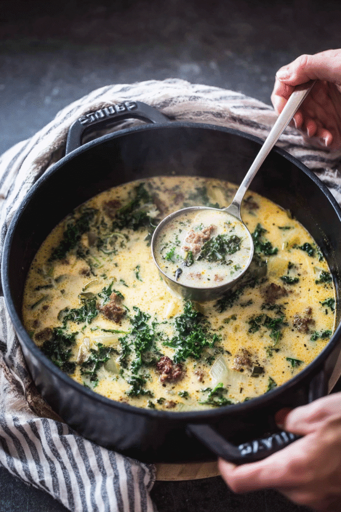 Creamy Tuscan soup with sausage, kale, and potatoes simmered in a rich broth, served warm in a black pot