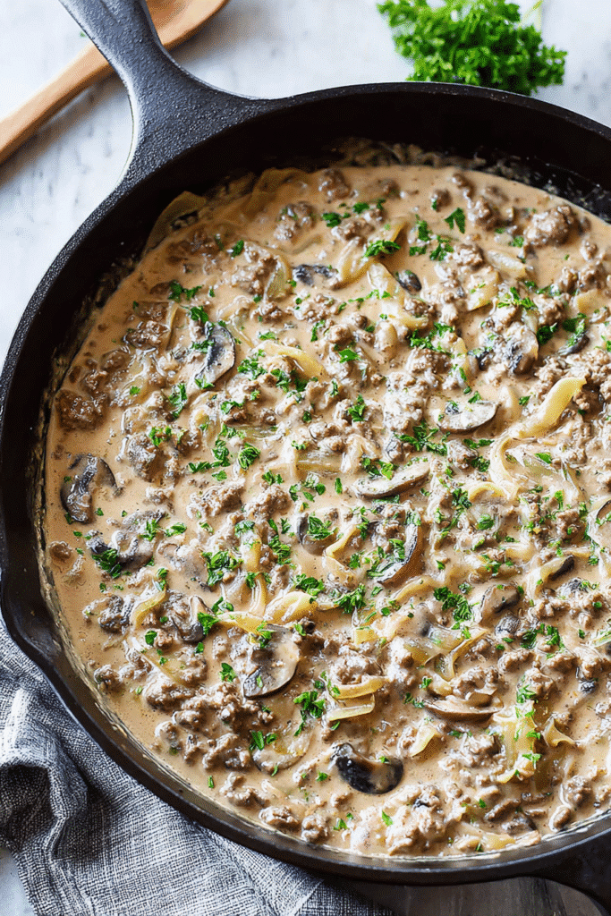 Creamy ground beef stroganoff with mushrooms and egg noodles in rich sauce, garnished with fresh parsley